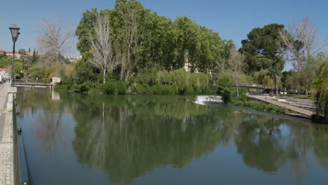 Scenic-tranquil-view-of-a-bridge-crossing-the-Nabão-River-surrounded-by-trees-in-Tomar-city-centre