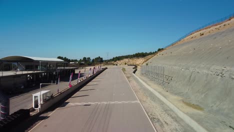 Cars-driving-on-castelloli-speed-circuit-on-a-sunny-day,-aerial-view