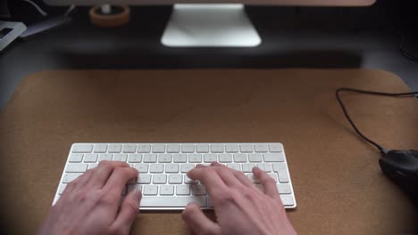 Man-working-behind-his-desk-typing-on-his-keyboard
