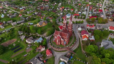 Una-Histórica-Iglesia-De-Ladrillo-Rojo-Rodeada-Por-Un-Pequeño-Pueblo-En-Lituania,-Vista-Aérea