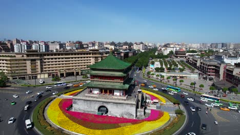 Colourful-Bell-Tower-roundabout-surrounded-by-flowers-and-cars,-Xian,-China