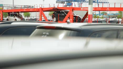 Verschwommene-Autos-Bei-Einem-Händler-Mit-Deutlichen-Roten-Strukturen-Von-DB-Schenker-Im-Hintergrund