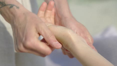 Una-Mano-Tatuada-Dando-Un-Masaje-Relajante-En-Un-Día-Soleado-En-La-Playa,-Primer-Plano