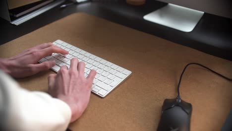 Man-behind-standing-desk,-typing-on-his-keyboard,-working-in-his-office