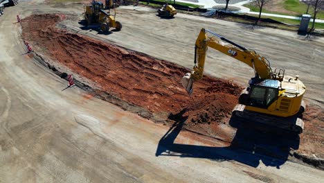 Aerial-Drone-Tracking-Track-hoe-As-The-Operator-Plays-With-Dirt-And-Teases-Dump-Truck-Driver-That-He-Will-Dump-Dirt-Into-His-Load-Of-Clean-Gravel-By-Mistake