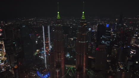 Aerial-tilt-shot-rotating-in-front-of-the-Petronas-Twin-Towers,-night-in-KL,-Malaysia