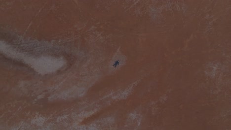 Birdseye-drone-clip-of-remote-Australian-desert,-with-male-model-lying-on-ground-supine