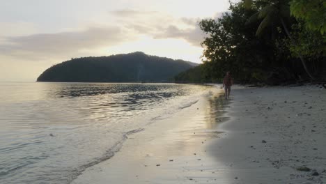 A-man-walks-along-the-tranquil-beach-of-Kri-Island-in-the-Raja-Ampat-archipelago,-Indonesia