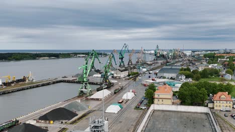 Klaipeda-docks-with-cranes-and-cargo-containers-on-a-cloudy-day,-aerial-view