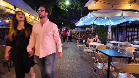 Bustling-nightlife-scene-at-outdoor-cafes-in-Medellin's-Provenza-neighborhood,-vibrant-evening