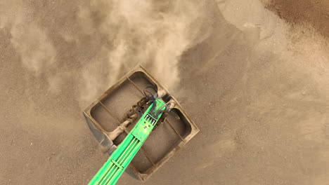 A-close-up-aerial-view-of-an-excavator's-scoop-filling-with-sand,-highlighting-the-texture-and-movement