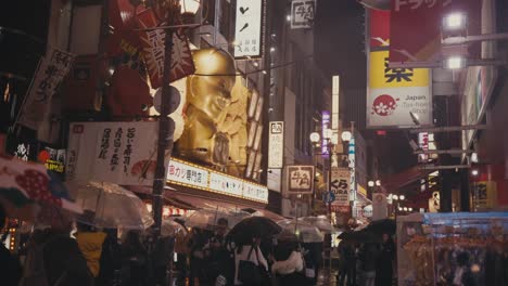 Dotonbori-Straße-In-Einer-Regnerischen-Nacht-Mit-Menschenmenge-In-Osaka,-Japan