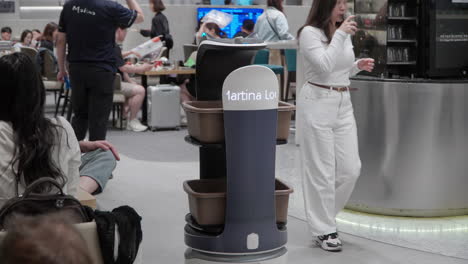 Robot-Inteligente-Recogiendo-Platos-Sucios-Moviéndose-Evitando-A-La-Gente-En-El-Salón-Martina,-Aeropuerto-De-Incheon