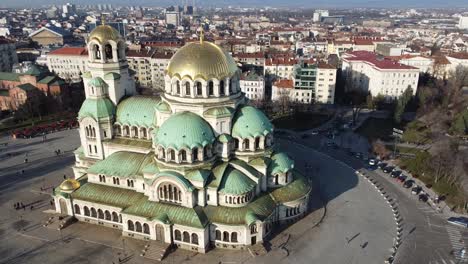 Faster-aerial-orbital-drone-clip-circling-around-Alexander-Nevsky-Cathedral-anti-clockwise-in-the-Winter-sun-with-the-city-of-Sofia,-Bulgaria-in-the-background