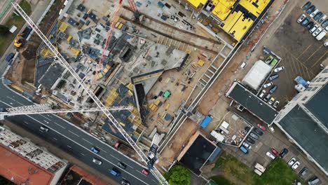 A-busy-urban-construction-site-with-vehicles-passing-by-on-the-road,-aerial-view
