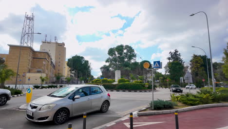 A-roundabout-in-Nicosia,-Cyprus,-with-a-mix-of-modern-and-traditional-buildings,-featuring-a-clear-sky-and-cars-passing-by,-slow-motion