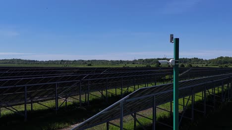 A-security-camera-watches-over-a-large-solar-panel-farm-under-a-clear-blue-sky