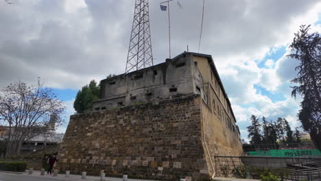 A-historic-fortification-in-Nicosia,-Cyprus,-with-an-old-stone-wall-and-a-modern-communications-tower,-captured-in-slow-motion