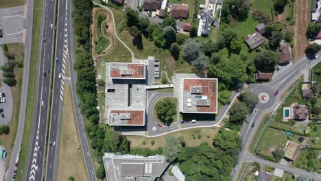 Top-down-aerial-of-large-apartment-complex-with-a-road-leading-to-a-subterranean-car-park