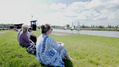 Female-spectators-watch-yacht-club-sail-boat-race-River-Waveney,-Suffolk