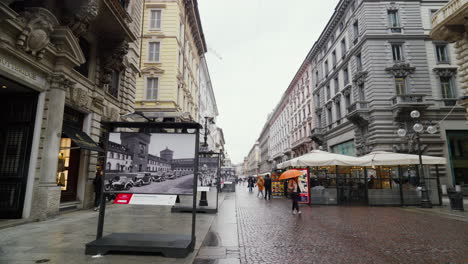 Rainy-day-in-Milan-showcasing-shopping-street-with-historical-exhibit-and-cyclist
