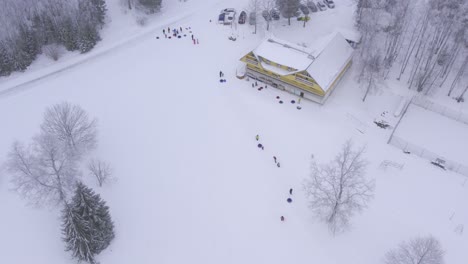 Drone-flight-over-crown-who-are-enjoying-winter-leisure-by-sliding-down-from-hill