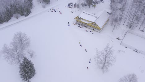 Vuelo-De-Drones-Sobre-La-Corona-Que-Disfrutan-Del-Ocio-Invernal-Deslizándose-Desde-La-Colina