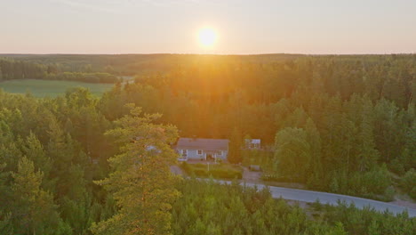 Drohnenaufnahme-Eines-Autarken-Hauses-Inmitten-Dichter-Wälder,-Sommersonnenaufgang