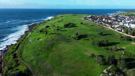 Landscape-pan-of-trees-on-Randwick-Malabar-Golf-course-greens-fairway-by-coastline-oceanside-sea-waves-headland-Sydney-Australia-drone-aerial