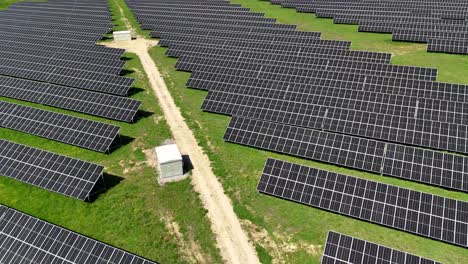 Solar-panels-arranged-in-a-field-under-bright-sunlight,-aerial-view