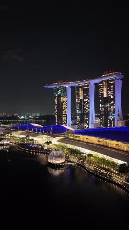 Wide-riverfront-view-of-the-famous-Marina-Bay-Sands-resort-in-Singapore,-vertical-aerial-video