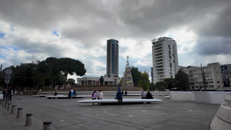 A-bustling-public-square-in-Nicosia,-Cyprus,-with-modern-seating-areas-and-a-backdrop-of-tall-buildings,-captured-in-slow-motion