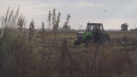 Handheld-view-of-a-tractor-approaching-while-sowing-the-soil-in-preparation-for-sowing