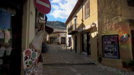 A-narrow,-cobblestone-street-lined-with-shops-and-buildings-in-Lefkara,-Cyprus,-under-a-blue-sky