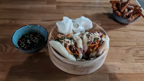 Steamed-bao-buns-with-pickled-vegetables-and-sauce-on-a-wooden-table