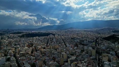 Sun-is-shinning-on-Athens-city-through-stormy-clouds,-aerial-drone-view