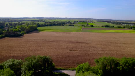 Verdant-and-harvested-fields-split-by-tree-lines-in-Bernis,-France---aerial