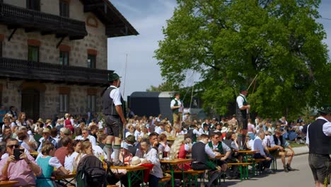 Jährliche-Traditionelle-Bayerische-Maifestfeier-Mit-Menschen,-Maibaum,-Peitschen,-Lederhosen