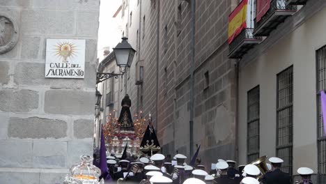 Una-Carroza-De-&quot;paso&quot;-Que-Se-Balancea-Suavemente-En-La-Distancia-Mientras-Recorre-Madrid,-Seguida-Por-Una-Banda-De-Música-Durante-Las-Celebraciones-De-Semana-Santa