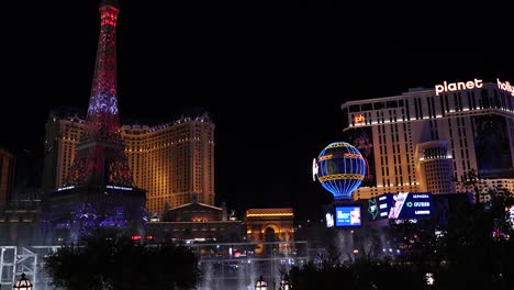 Las-Vegas-Cityscape-Skyline-at-Night,-Bellagio-Fountain,-Paris-Hotel-Casino-Buildings-in-Lights,-Eiffel-Tower-and-Balloon-Replica