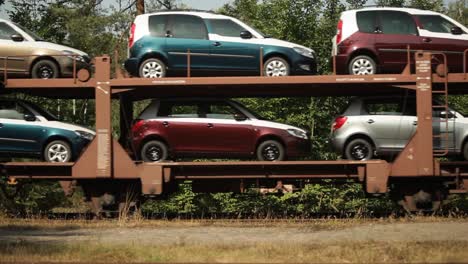 Tren-De-Transporte-De-Automóviles-En-Movimiento-A-Través-De-Un-Paisaje-Natural.