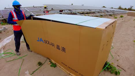 Technician-opens-a-box-palette-of-brand-new-bifacial-solar-panels-to-install-new-solar-panels-for-renewable-energy-generation
