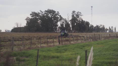 Handheld,-wide-view-of-a-tractor-approaching-while-sowing-the-soil-in-preparation-for-sowing