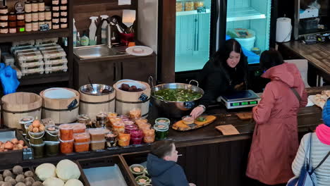 Agenskalns-Market-staff-as-woman-buys-food-from-cafe-store,-high-angle-view-looking-down