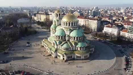 Clip-Aéreo-Orbital-De-Drones-Dando-Vueltas-Alrededor-De-La-Catedral-De-Alexander-Nevsky-En-El-Sentido-De-Las-Agujas-Del-Reloj-Bajo-El-Sol-De-Invierno-Con-La-Ciudad-De-Sofía-Y-Stara-Planina,-Bulgaria-Al-Fondo