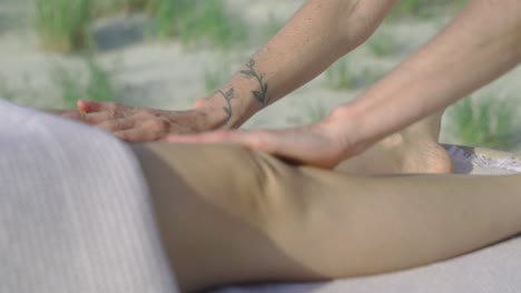 Frau-Gibt-An-Einem-Sonnigen-Tag-Eine-Entspannende-Beinmassage-Am-Strand