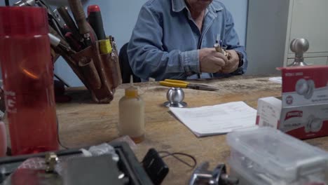 Latin-locksmith-man-working-at-the-workshop-table,-with-tools-for-repair-and-maintenance-of-door-locks