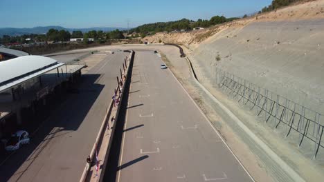 Coches-Corriendo-En-Un-Día-Soleado-En-El-Circuito-De-Velocidad-Castelloli-En-Barcelona-Con-Pintorescas-Montañas-Al-Fondo