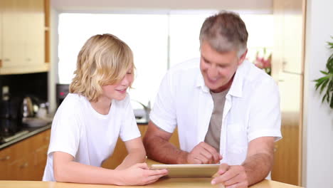 Padre-E-Hijo-Con-Una-Tableta-En-La-Cocina