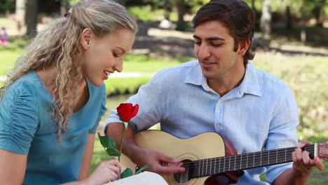 Un-Hombre-Le-Da-Una-Serenata-A-Su-Novia-Con-Una-Canción-Mientras-Ella-Sostiene-Una-Rosa-Mientras-Miran-A-La-Cámara